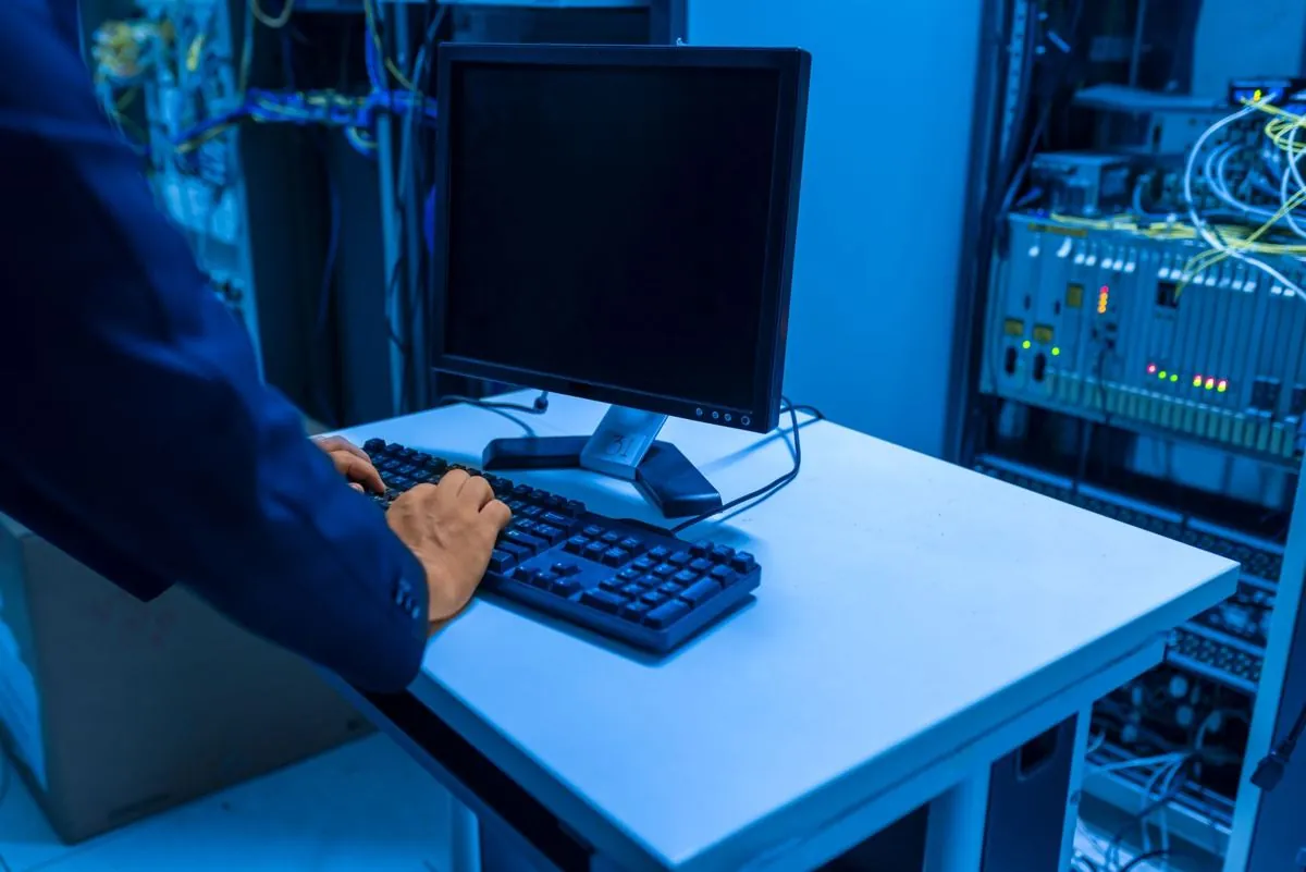 Un tecnico che mette le mani fra i cavi di un armadio server