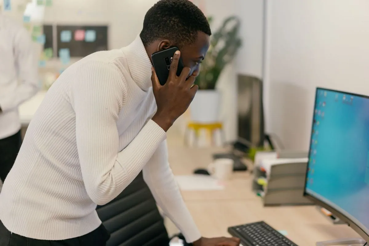 Uomo al telefono davanti al computer mentre guarda lo schermo