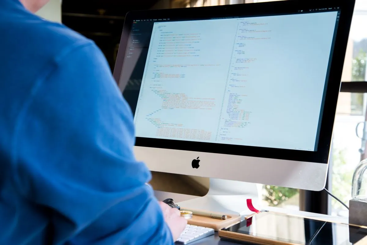 Righe di codice su un monitor in mezzo alle carte dell’ufficio