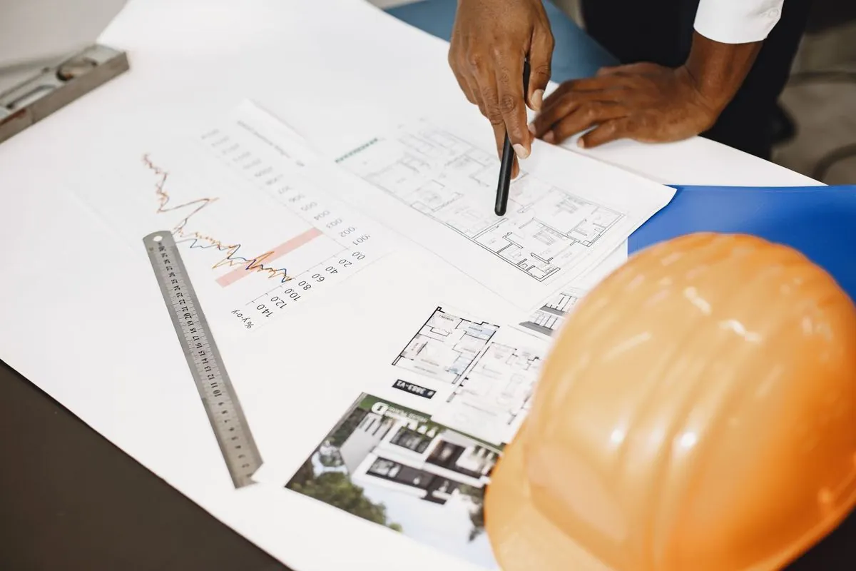 Disegni di cantiere e bolle impolverate stesi su un tavolo da lavoro